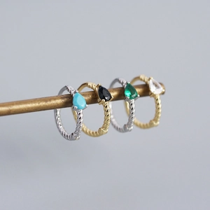 Close-up of twist metal hoop earrings with teardrop gemstones in varied colors