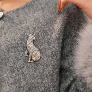 Nahaufnahme einer Vintage Silber Katzenbrosche mit gravierter Metallstruktur auf grauem Pullover