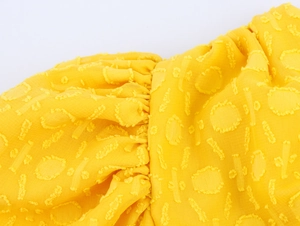 Detailaufnahme von gelbem Stoff mit Raffungen und strukturiertem Polka-Dot-Jacquard