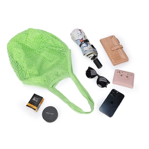 Flat lay of a green mesh tote bag with daily items showing large storage capacity
