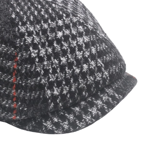 Detail of wool houndstooth newsboy cap featuring a unique vertical red stitch accent
