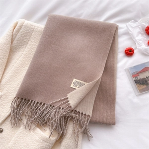 Detail of soft double-sided beige and brown cashmere scarf with fringe and brand label