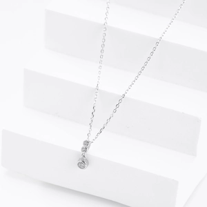 Macro view of minimalist silver necklace with three vertical clear cubic zirconia stones