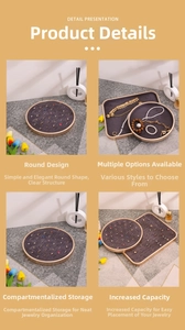 Detail of round beige jewelry tray with gold metal frame and dark grey velvet slots