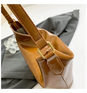 Detail shot of brown glossy textured tote with gold hardware on a stylish side view