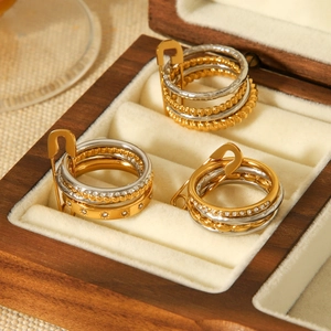 Stacked stainless steel rings with pin charms and crystals in a wooden jewelry box