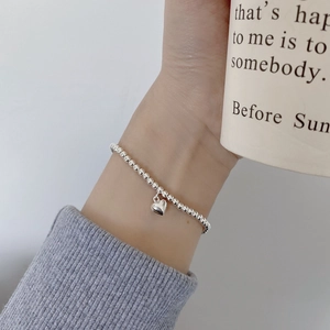 Detailopname van minimalistische zilveren kralenarmband met hartje om de pols