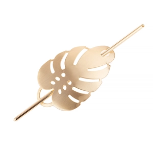 Detailed close-up of a golden hollowed monstera leaf metal hair pin on white background