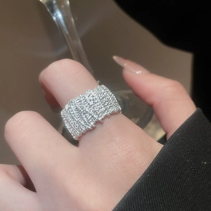 Macro shot of silver wide band ring featuring intricate woven texture on female finger