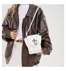 Detail view of the white crossbody bag featuring gothic cross and star metal hardware.