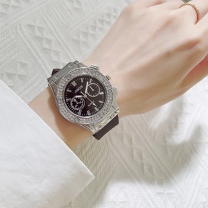 Close-up of sparkling diamond-encrusted bezel and black dial on a silicone wrist watch