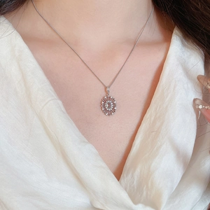 Close-up of elegant silver necklace with oval sunburst pendant worn by a model