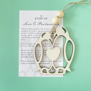 Detail of wooden penguin ornament with sentimental story card on a mint green background