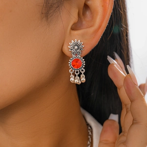 Close-up of vintage flower earrings with red gemstone and silver tassels on model