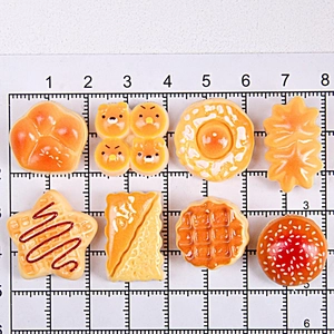 Detailed assortment of miniature resin food charms displayed on a measurement grid