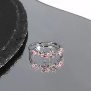 Detail of silver wreath ring with pink bow and heart-shaped zircon on reflective stone