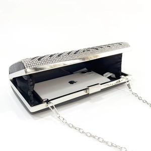 Detail view of the black and silver rhinestone clutch with a silver chain and phone inside
