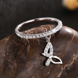 Macro shot of silver butterfly charm ring with sparkling zircon stones on natural stone