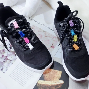 Black sneakers with colorful gummy bear charms on polka dot laces on a lifestyle magazine