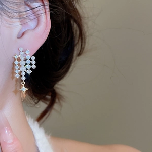Elegant model wearing a gold star pearl earring with sparkling zircons on warm background