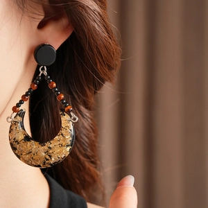 Close-up of vintage crescent resin earrings with gold foil details on a model