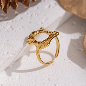 Detail of gold irregular ring with molten lava texture on white stone pedestal