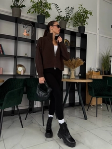 Details einer dunkelbraunen Strickjacke mit Reißverschluss, schwarzen Boots und Tasche