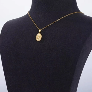 Vintage gold stainless steel sun pendant necklace on a black velvet jewelry display