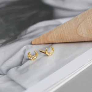 Detailed macro shot of golden crescent moon earrings with inlaid zircon stones