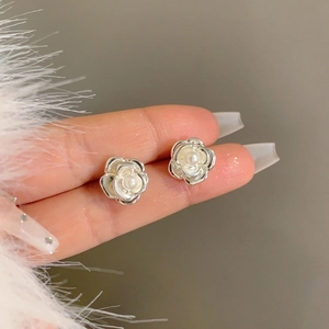 Detailed macro view of silver camellia flower earrings featuring a central white pearl