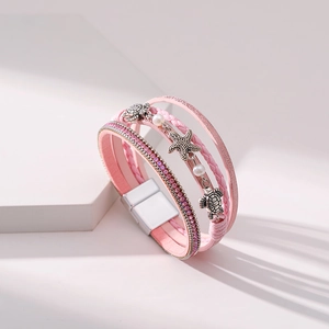 Close-up of pink layered leather bracelet featuring silver starfish and turtle charms