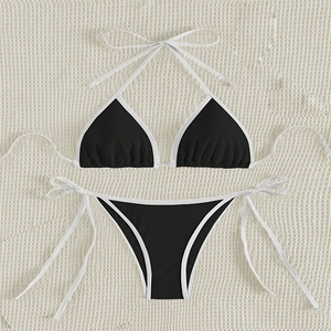 Detailed flat lay of black two-piece bikini with white trim on a textured knit background