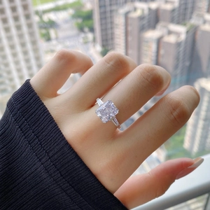 Close-up of a radiant cut square stone ring with side baguettes worn outdoors