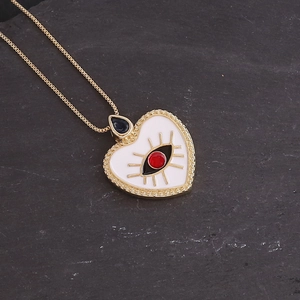 Detail of 18K gold heart pendant necklace with white enamel eye and blue gemstone clasp