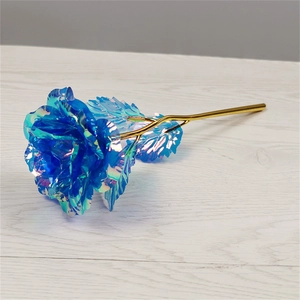 Macro shot of blue holographic rose with gold metallic stem on a wooden surface