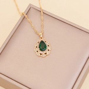 Close-up of gold water drop necklace with green gemstone and micro-pave diamonds