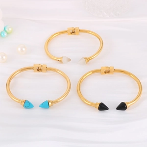 Detail of gold titanium steel rivet bracelets with white black and blue conical studs