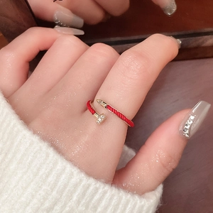 Detailed view of nail shaped ring in gold and red enamel worn on hand with crystal accents
