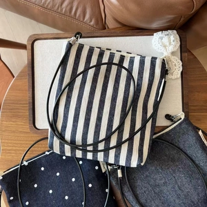Detailed set of striped, polka dot, and denim canvas crossbody mini bags on a wooden tray