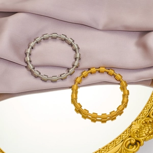 Detail of gold and silver spring coil bracelets on vintage mirror with silk backdrop