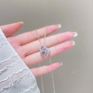Detail of silver heart projection necklace with white zircons on lace background