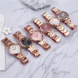 Detail of rose gold metal watches with multi-colored dials on white marble background