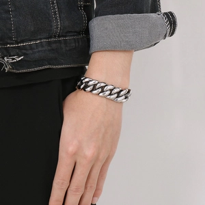 Close-up of thick silver stainless steel Cuban link bracelet worn on male wrist