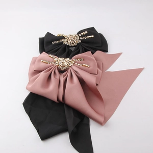 Detail of satin bow hair clips with rhinestone centers in black and dusty pink