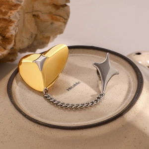 Detail of gold heart and silver star pins connected by chain on a ceramic stone background