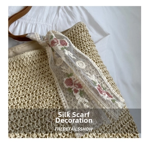 Detail view of woven straw bucket bag with white lace floral embroidery scarf