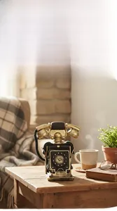Detail of vintage resin telephone model with antique gold finish on a wooden table