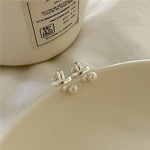 Minimalist 925 sterling silver knot earrings with round white pearls on a ceramic bowl