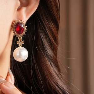 Gros plan de boucles d'oreilles vintage en or avec rubis rouge et perle blanche pendante