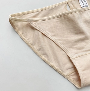 Detailed close-up of stitching and cotton fabric texture on beige women's sports briefs